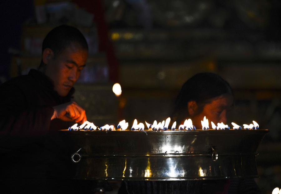 a monk lighting butter lamps in the Sakya Monastery.