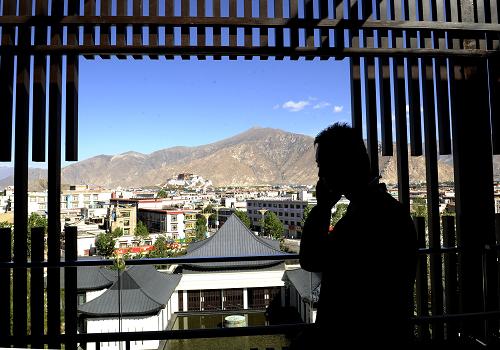 A visitor stands by the window of the St. Regis Resort Hotel in Lhasa