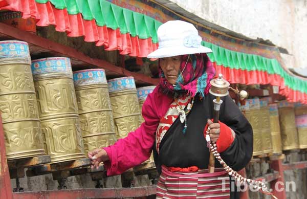 an old Tibetan woman turning prayer wheels along the ritual walk path in Lhasa during the Sagadawa festival.
