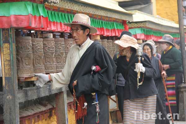 Tibetan pilgrims truning prayer wheels along the ritual walk path in Lhasa during Sagadawa celebration.