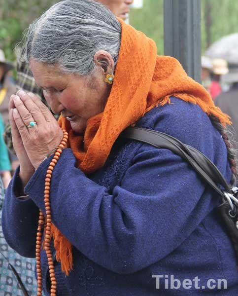 a Tibetan senior lady praying on her ritual walk in Lhasa