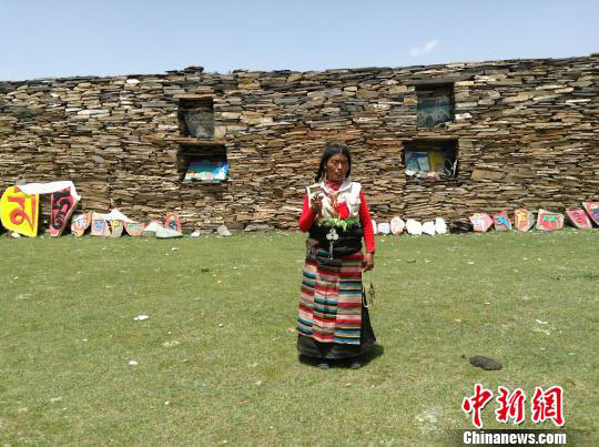 an old women in front of the Mani stone wall