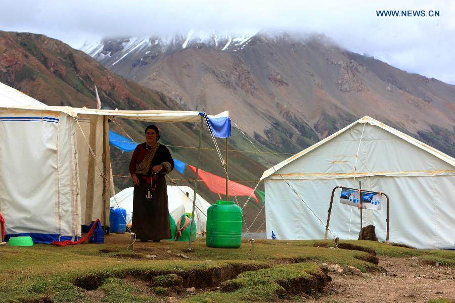 A woman of Tibetan ethnic group stands in front of her tent 