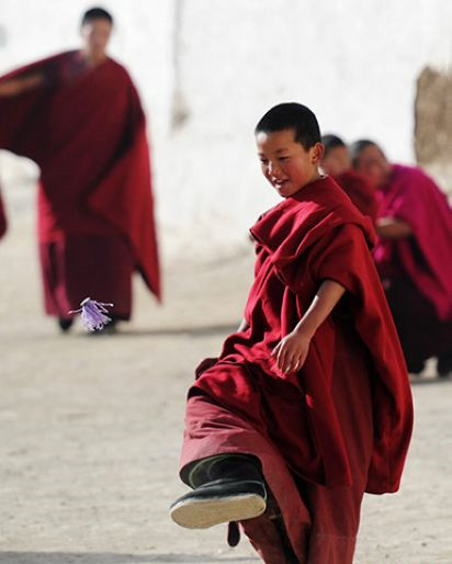 A young monk in red crimson robe in the Labrang Monastery kicks shuttlecock