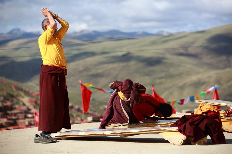 Monks in crimson robes are doing the full-body prostration to pay homage to the Buddha. 
