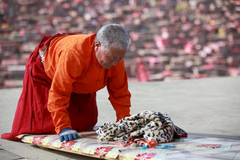 An elderly monk is doing the full-body prostration to pay homage to the Buddha. 