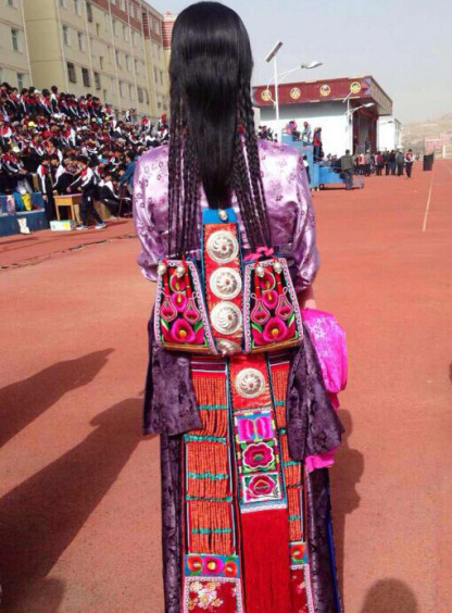 Photo shows traditional Tibetan styled braids of a dressed up girl.