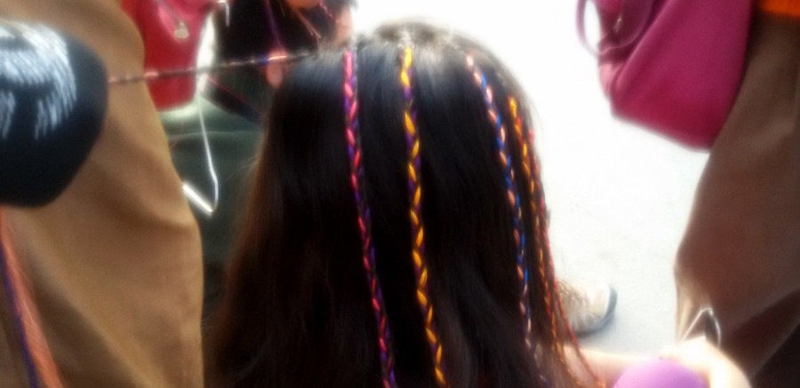Photo shows a girl having her hair braided. 