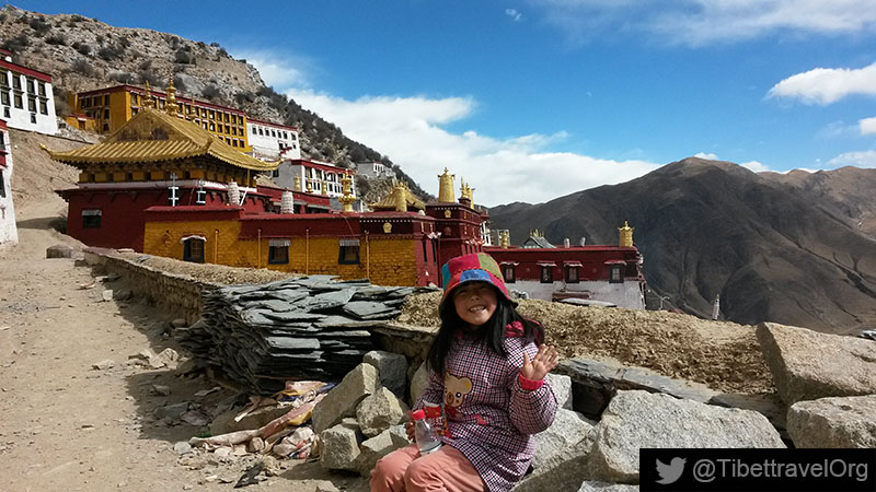 Angela was sitting in front of the Ganden Monastery, saying “hello” to everyone.