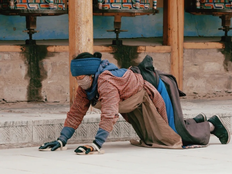 Tibetan Pilgrim Performing Prostration at a Tibetan Monastery Tibetan pilgrim performing full-body prostration at a monastery in Tibet