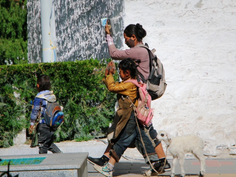 Tibetan Locals Practicing Religious Traditions in Lhasa Tibetan locals walking near a monastery in Lhasa